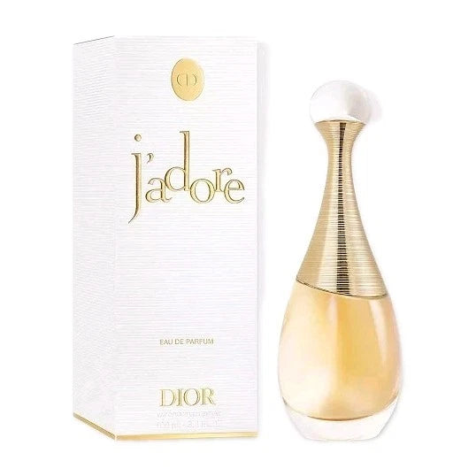 Dior J'adore Eau de Parfum bottle next to its white textured packaging box with gold lettering, on a plain white background.